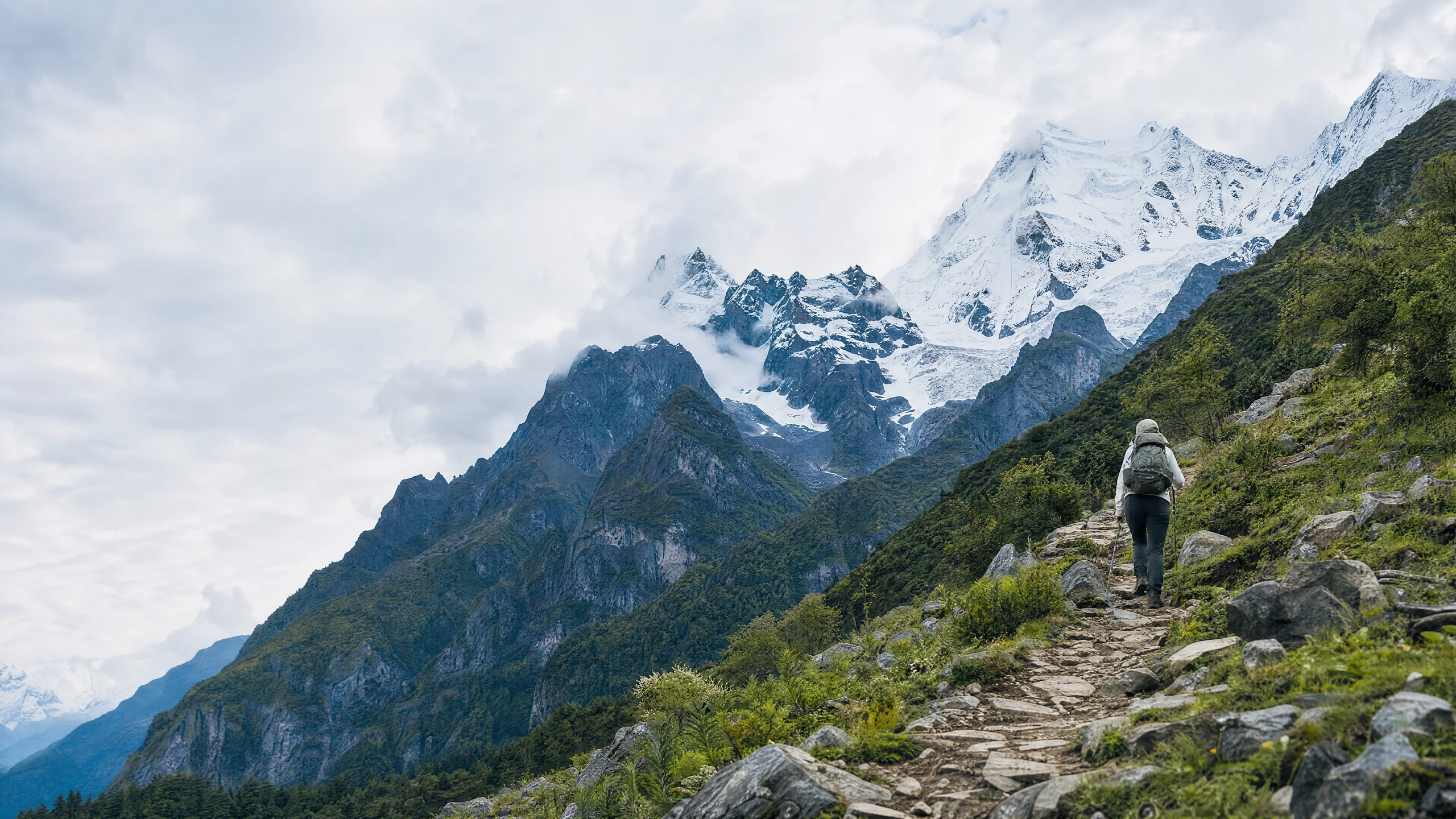 A walker on a stone trail beneath mountain peaks